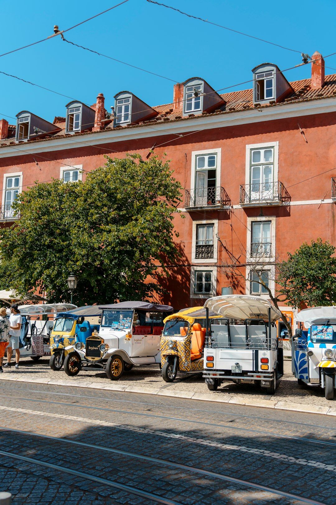 Line of vintage rally cars parked on a historic plaza