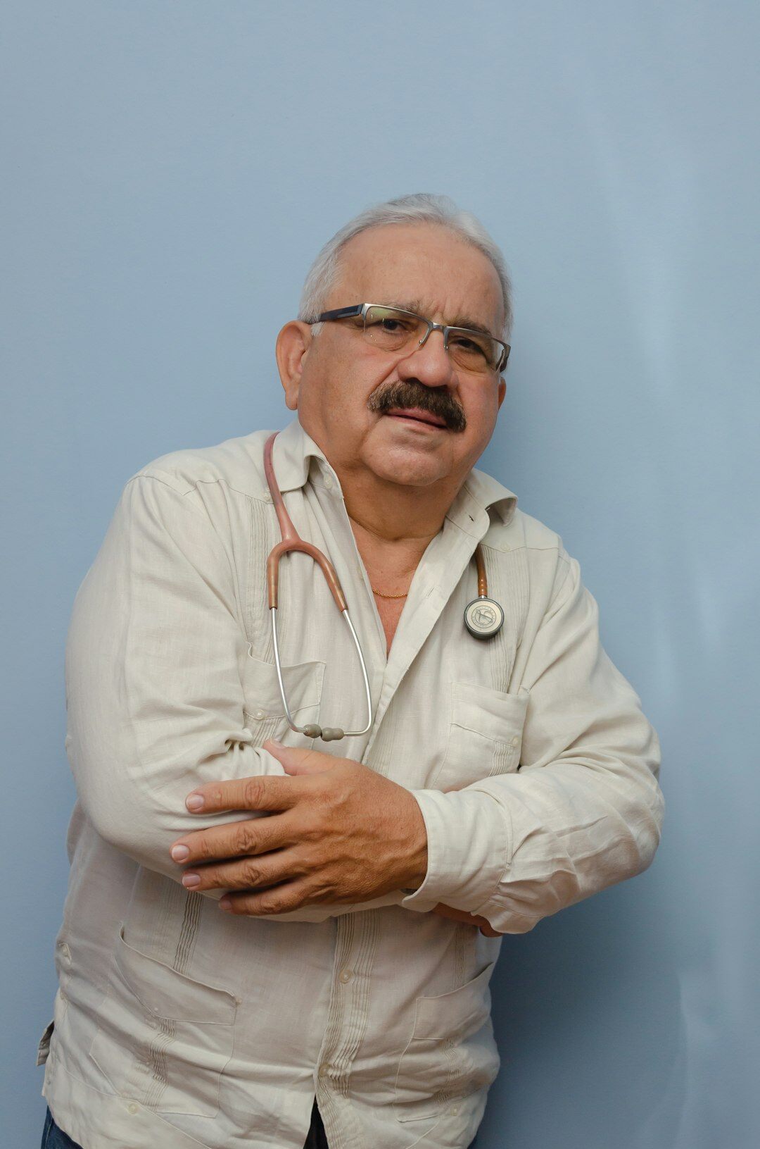 Studio portrait of an older Hispanic man with gray hair and glasses