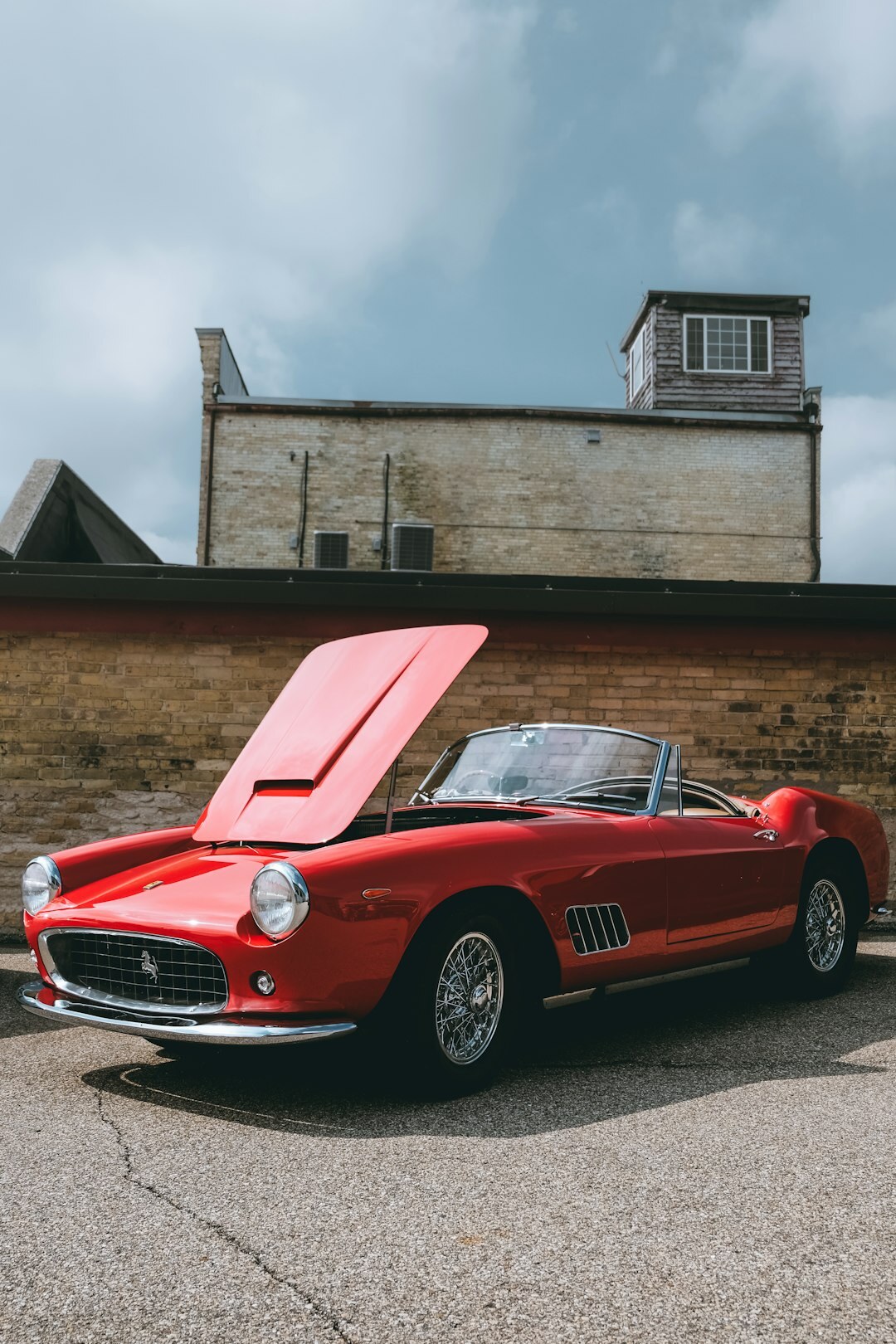 Red Italian classic sports car displayed under auction house lighting